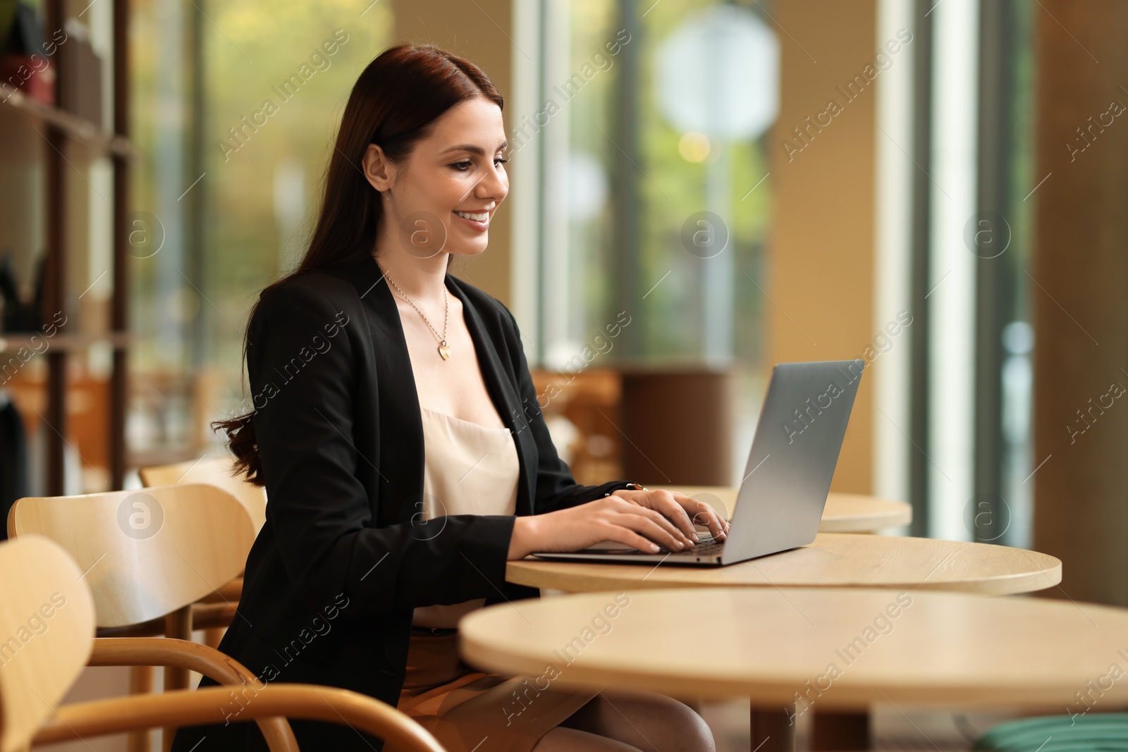 Photo of Woman in stylish formal suit working on laptop at table indoors