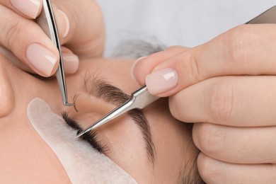 Photo of Woman undergoing lash extensions procedure in beauty salon, closeup