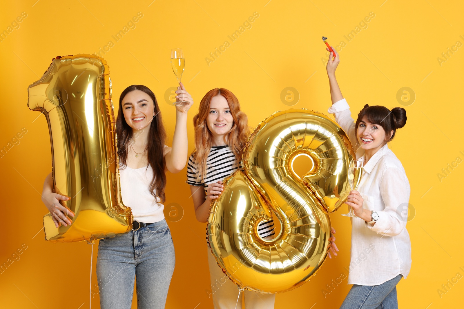 Photo of Coming of age party - 18th birthday. Group of young women celebrating with number shaped balloons on yellow background