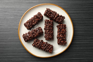 Photo of Delicious chocolate puffed rice bars on dark gray wooden table, top view