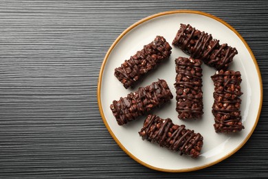 Photo of Delicious chocolate puffed rice bars on dark gray wooden table, top view. Space for text