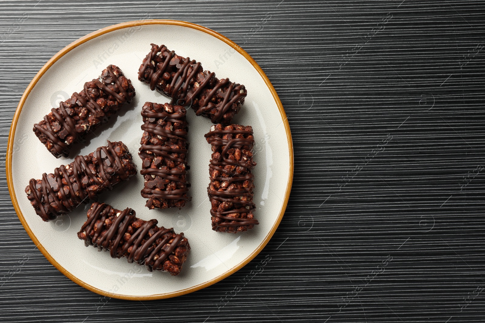 Photo of Delicious chocolate puffed rice bars on dark gray wooden table, top view. Space for text