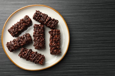 Delicious chocolate puffed rice bars on dark gray wooden table, top view. Space for text