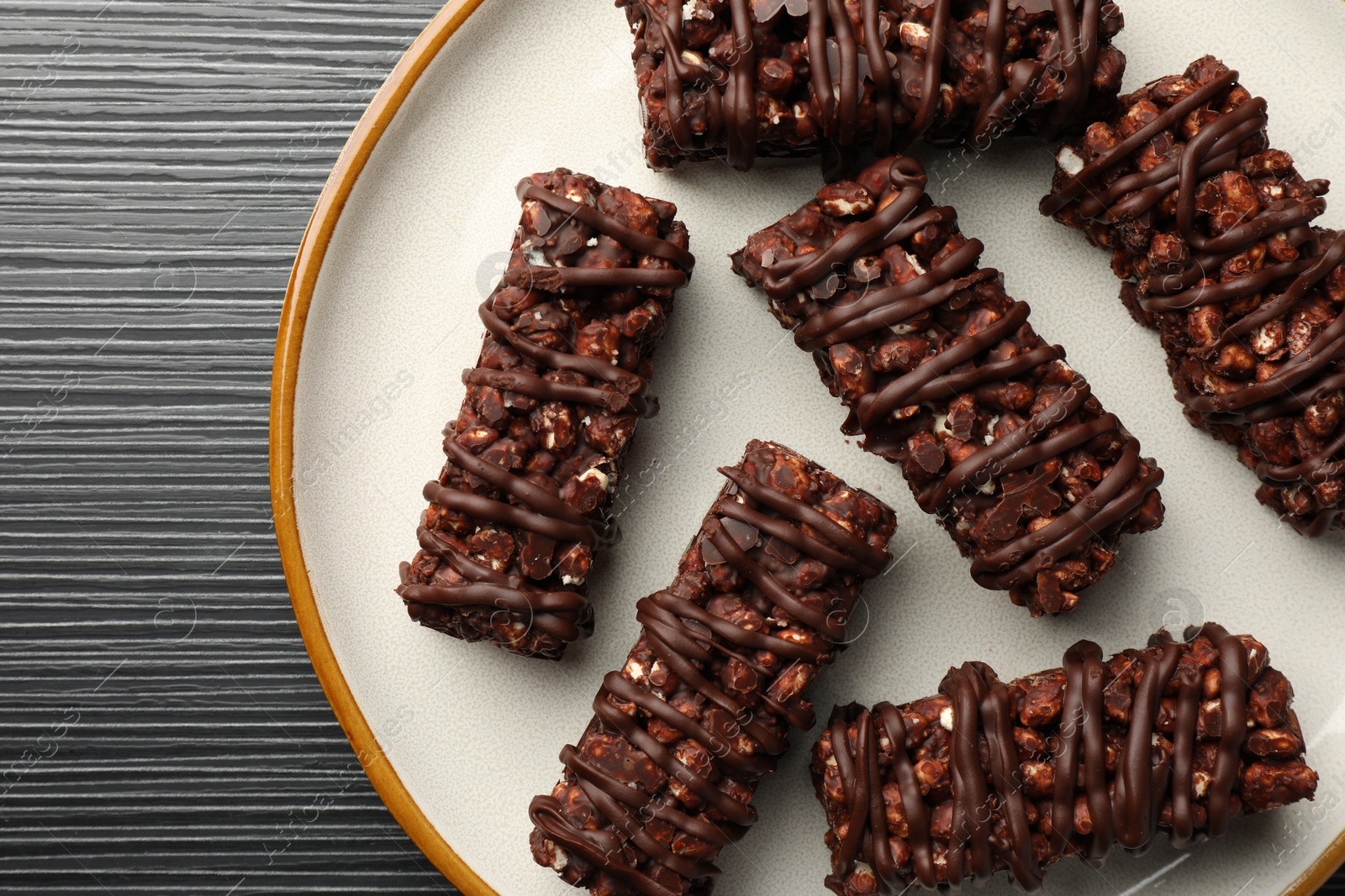 Photo of Delicious chocolate puffed rice bars on dark gray wooden table, top view