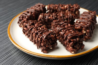 Photo of Delicious chocolate puffed rice bars on dark gray wooden table, closeup