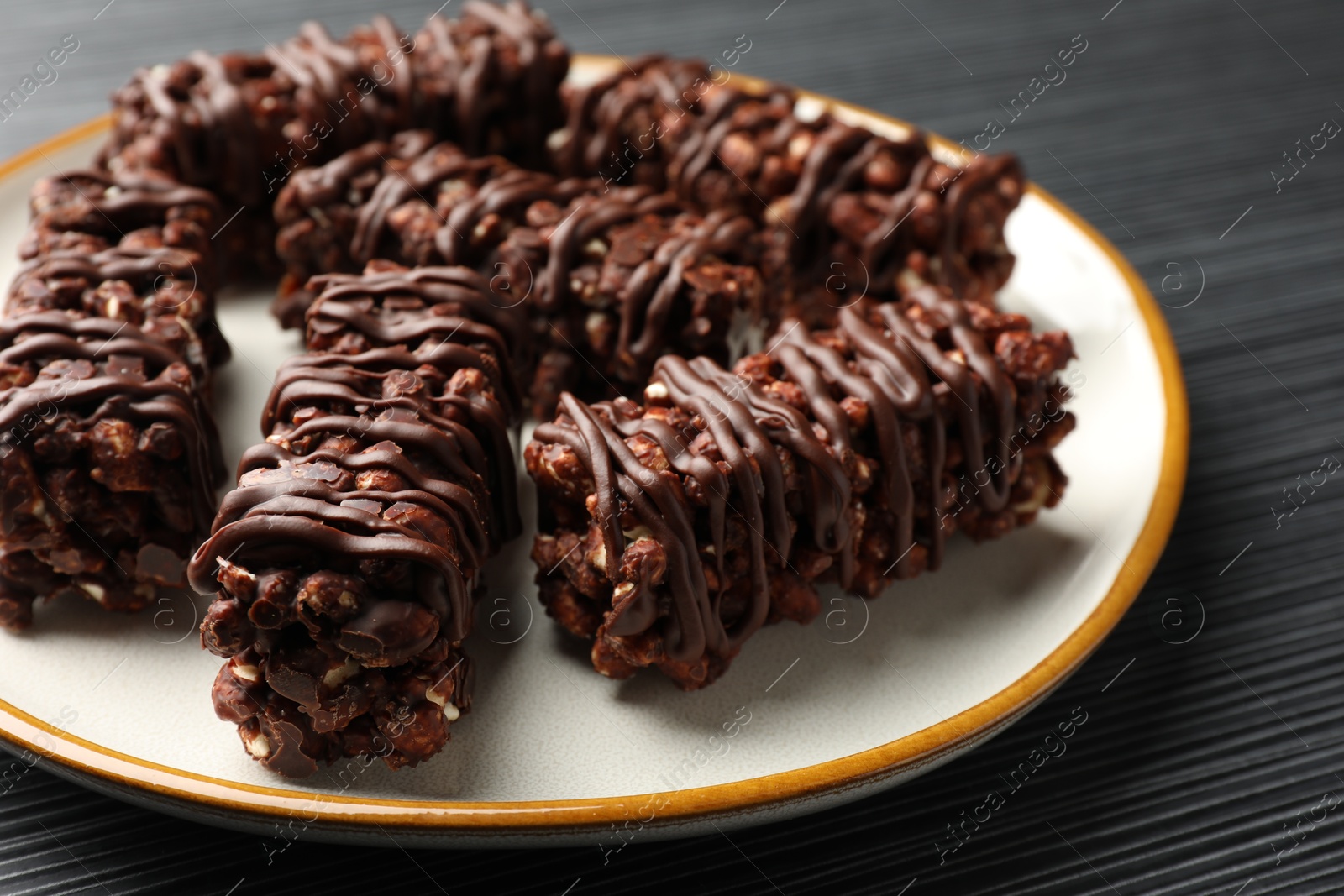 Photo of Delicious chocolate puffed rice bars on dark gray wooden table, closeup