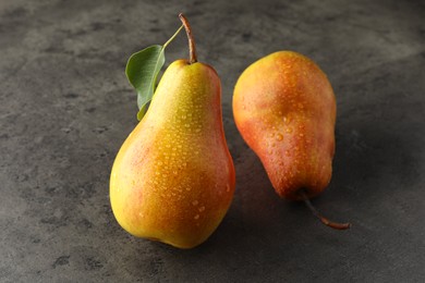 Photo of Two ripe juicy pears on grey table, closeup