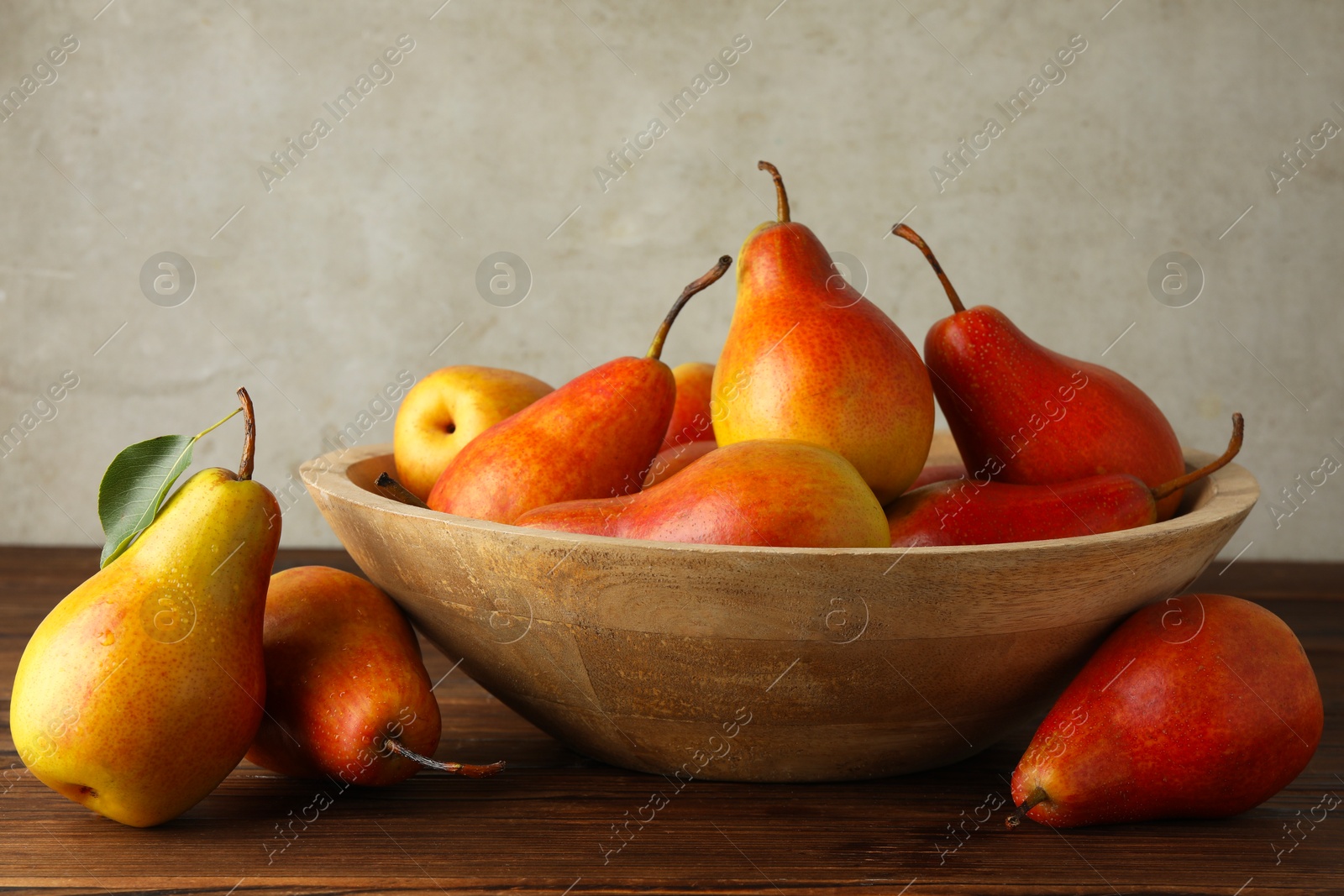 Photo of Ripe juicy pears in bowl on wooden table