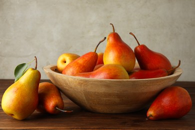 Photo of Ripe juicy pears in bowl on wooden table