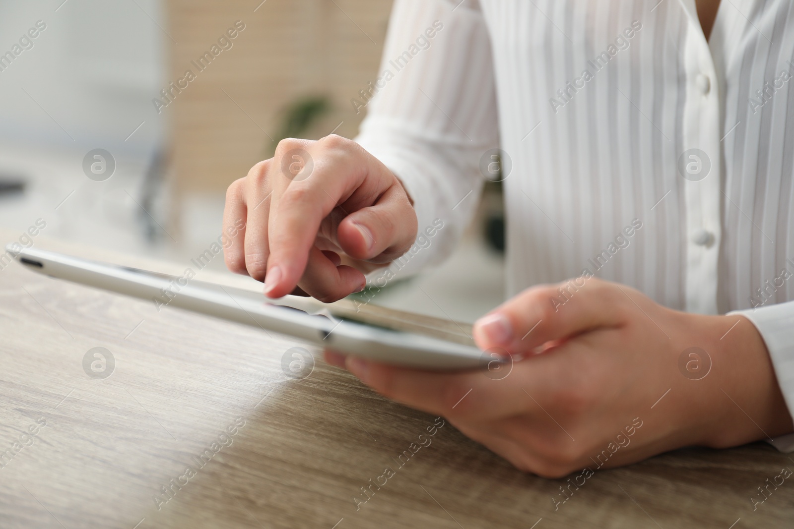 Photo of Businesswoman using tablet at wooden table indoors, closeup. Modern technology