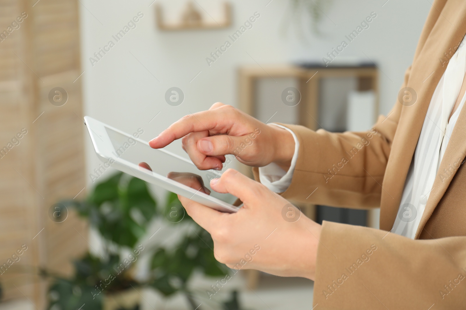 Photo of Businesswoman using tablet indoors, closeup. Modern technology