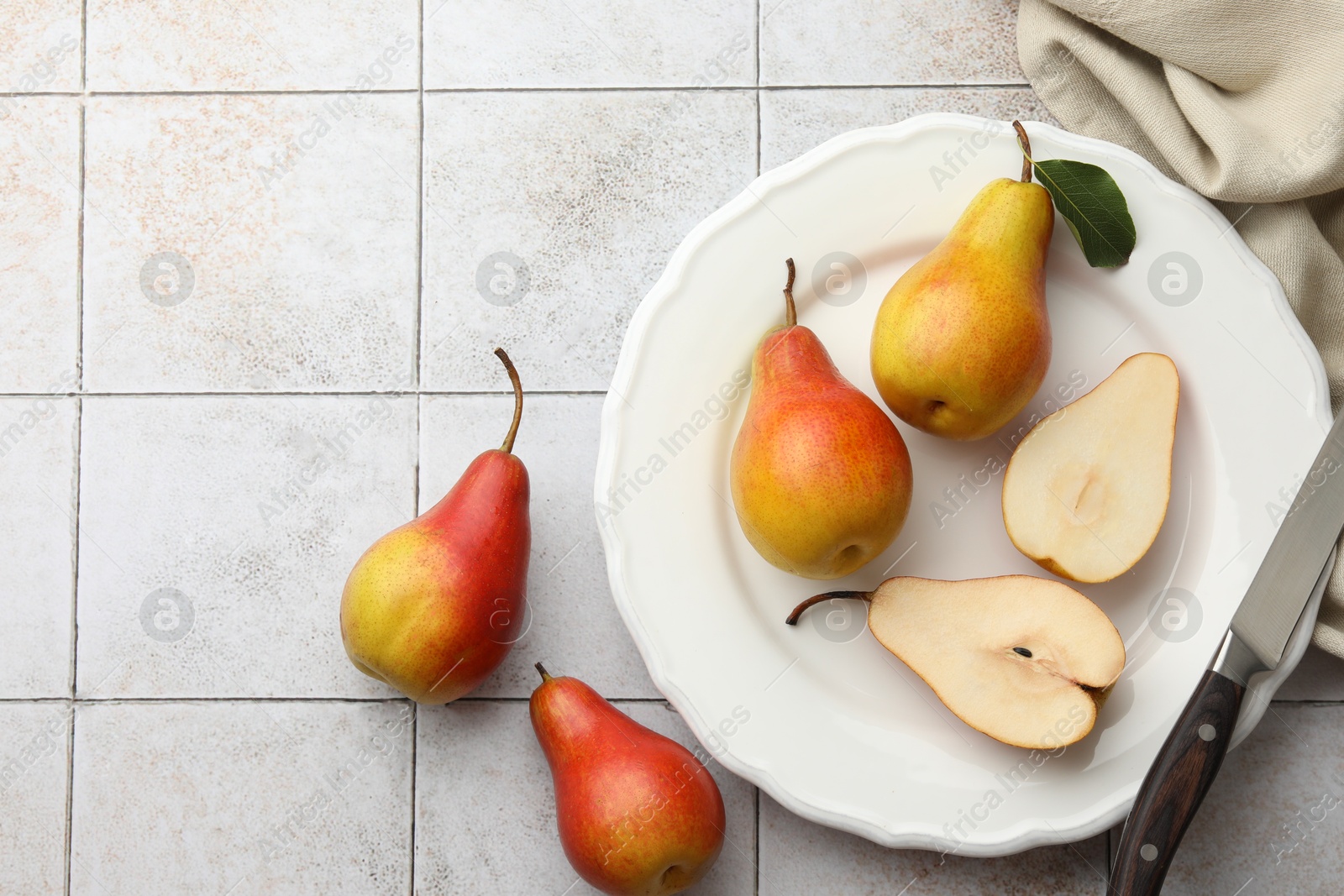 Photo of Ripe juicy pears on light tiled table, flat lay. Space for text