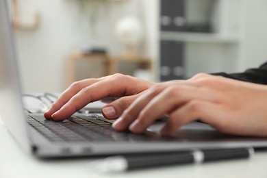 Photo of Businesswoman using laptop at table indoors, closeup. Modern technology