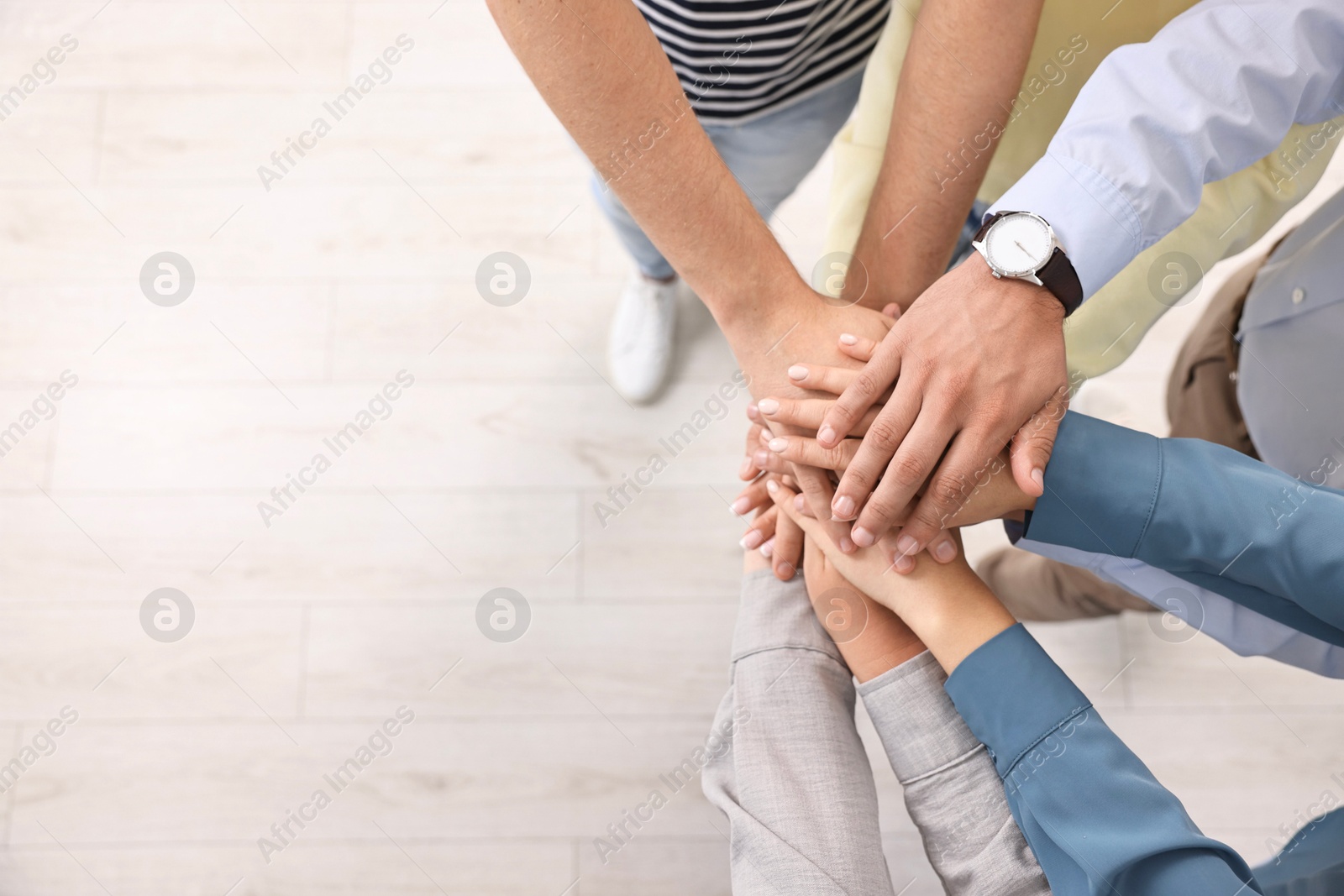 Photo of Teamwork. Group of employees joining hands in office, top view. Space for text