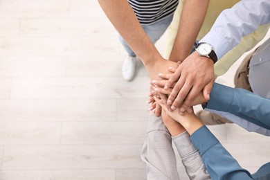 Photo of Teamwork. Group of employees joining hands in office, top view. Space for text