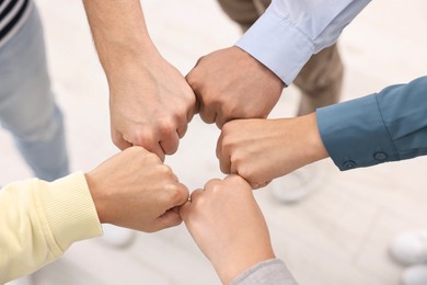 Photo of Teamwork. Group of employees joining hands in office, top view