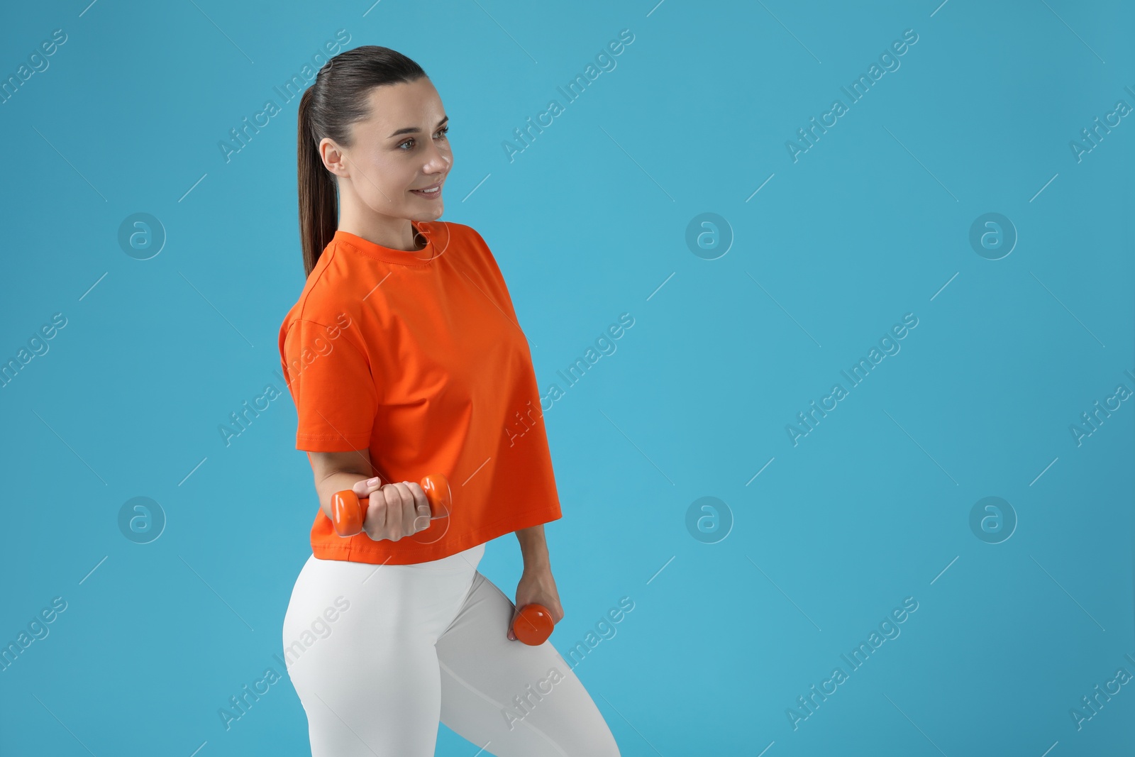 Photo of Woman exercising with dumbbells on light blue background, space for text