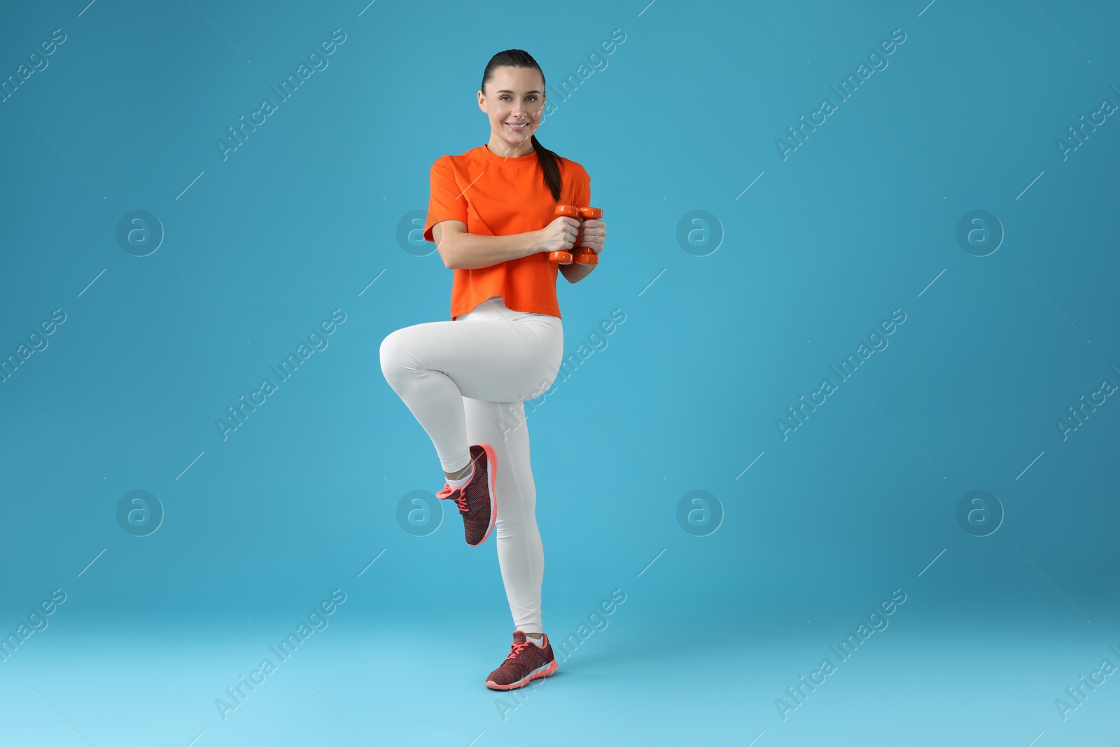 Photo of Woman exercising with dumbbells on light blue background, space for text