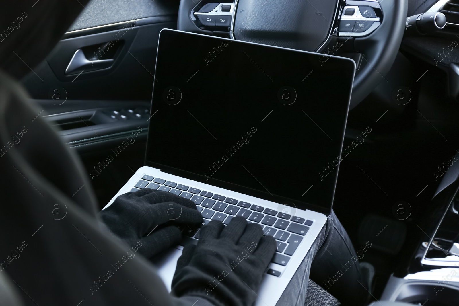 Photo of Thief hacking car system with laptop inside vehicle, closeup