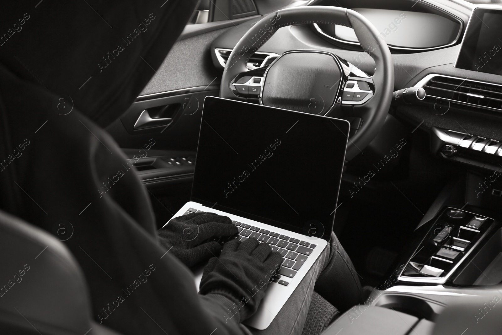 Photo of Thief hacking car system with laptop inside vehicle, closeup