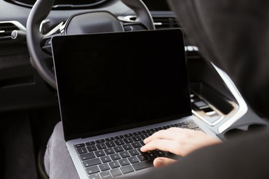 Photo of Thief hacking car system with laptop inside vehicle, closeup