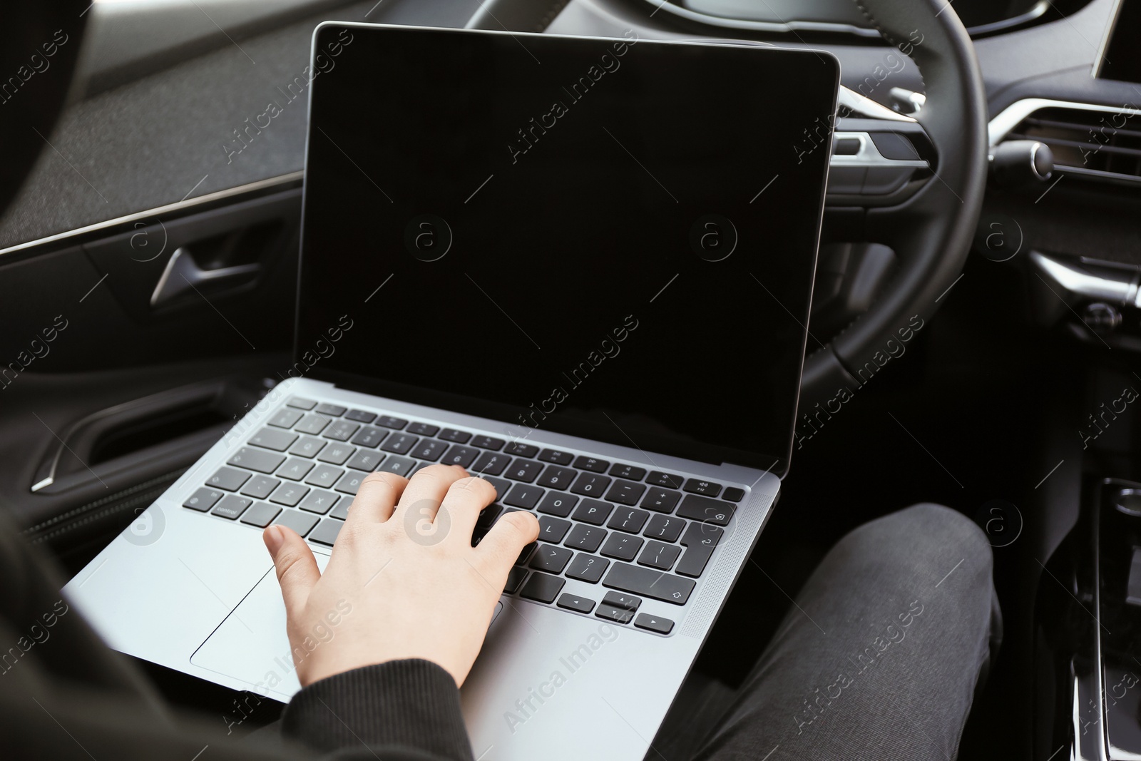 Photo of Thief hacking car system with laptop inside vehicle, closeup