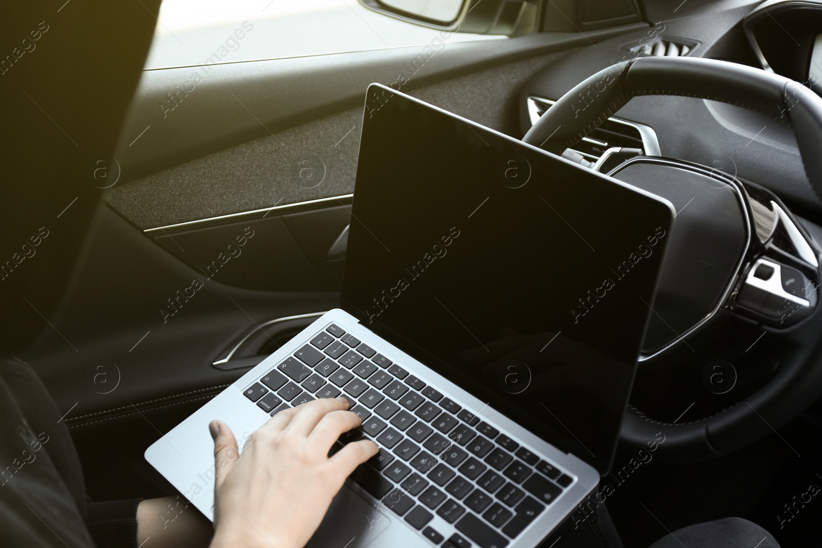 Photo of Thief hacking car system with laptop inside vehicle, closeup