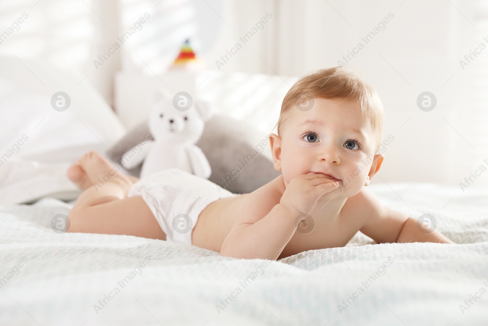 Photo of Cute little baby in diaper on bed at home