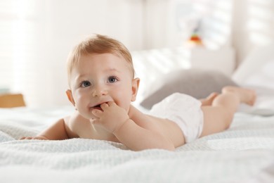 Cute little baby in diaper on bed at home