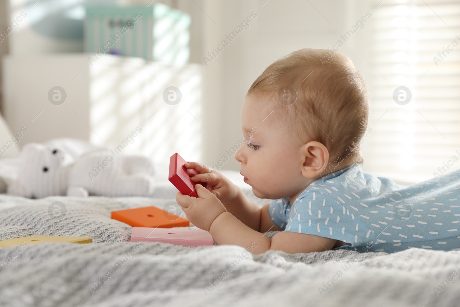 Photo of Cute little baby with toys on bed at home