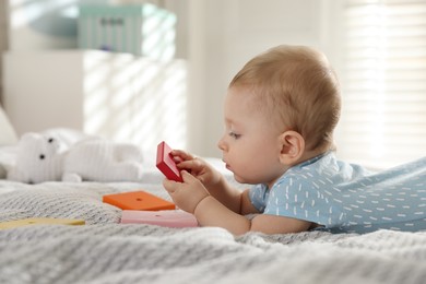 Cute little baby with toys on bed at home