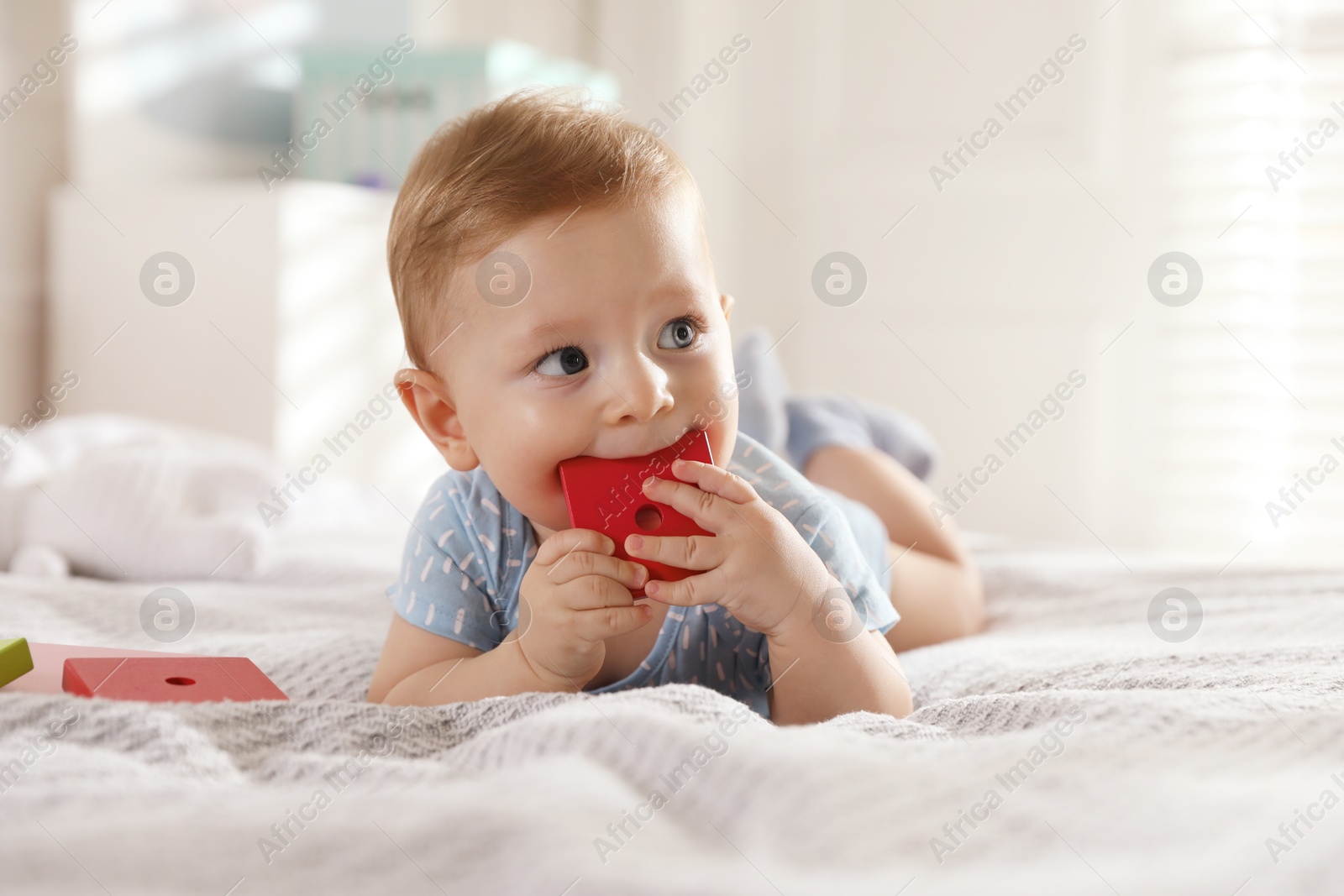 Photo of Cute little baby with toys on bed at home