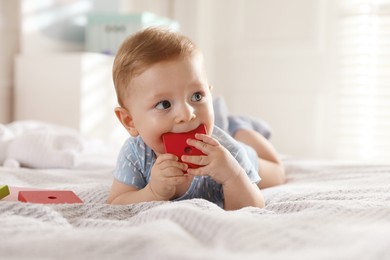 Cute little baby with toys on bed at home