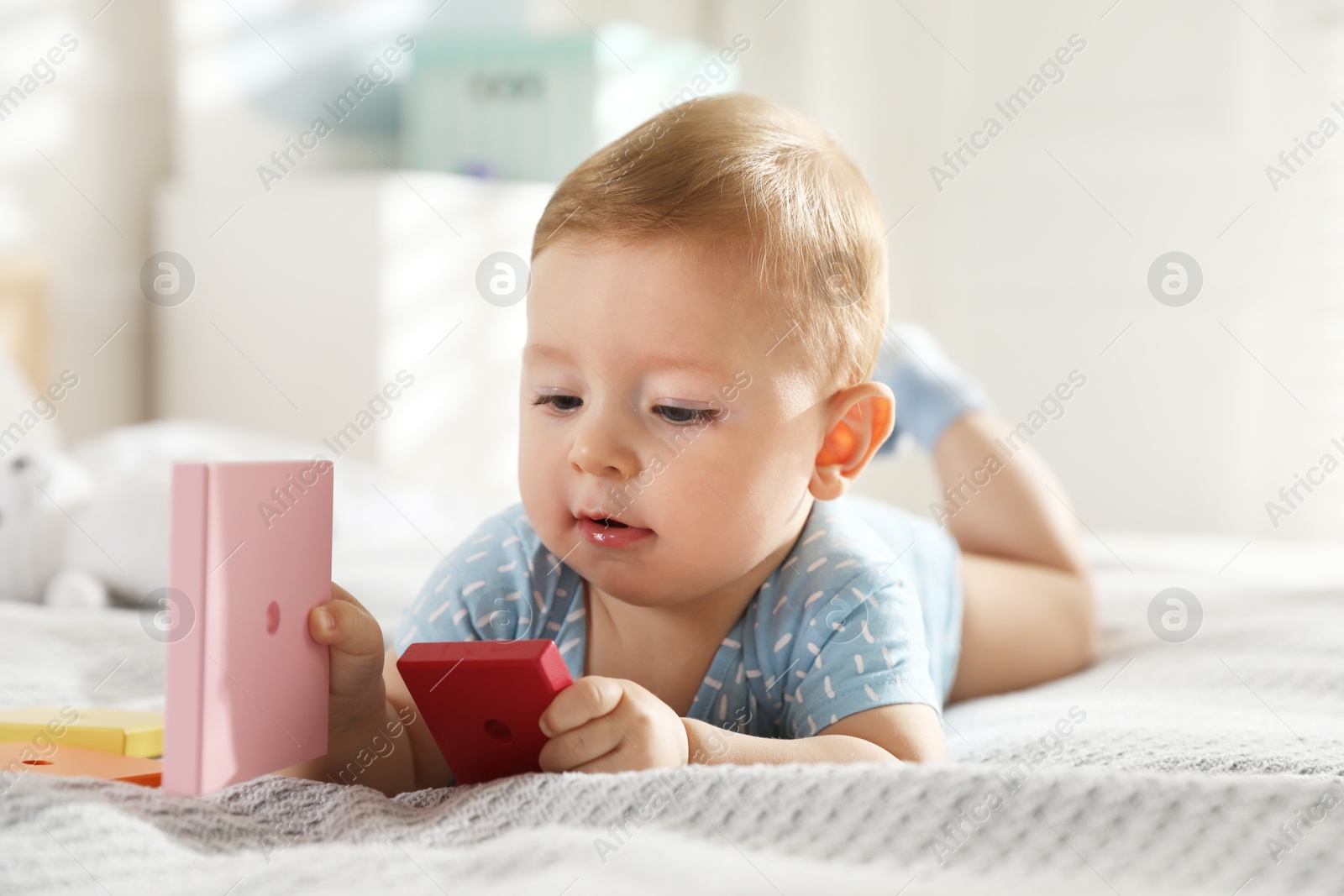 Photo of Cute little baby with toys on bed at home