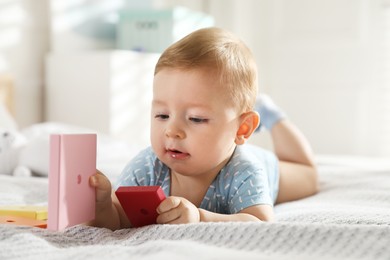 Cute little baby with toys on bed at home