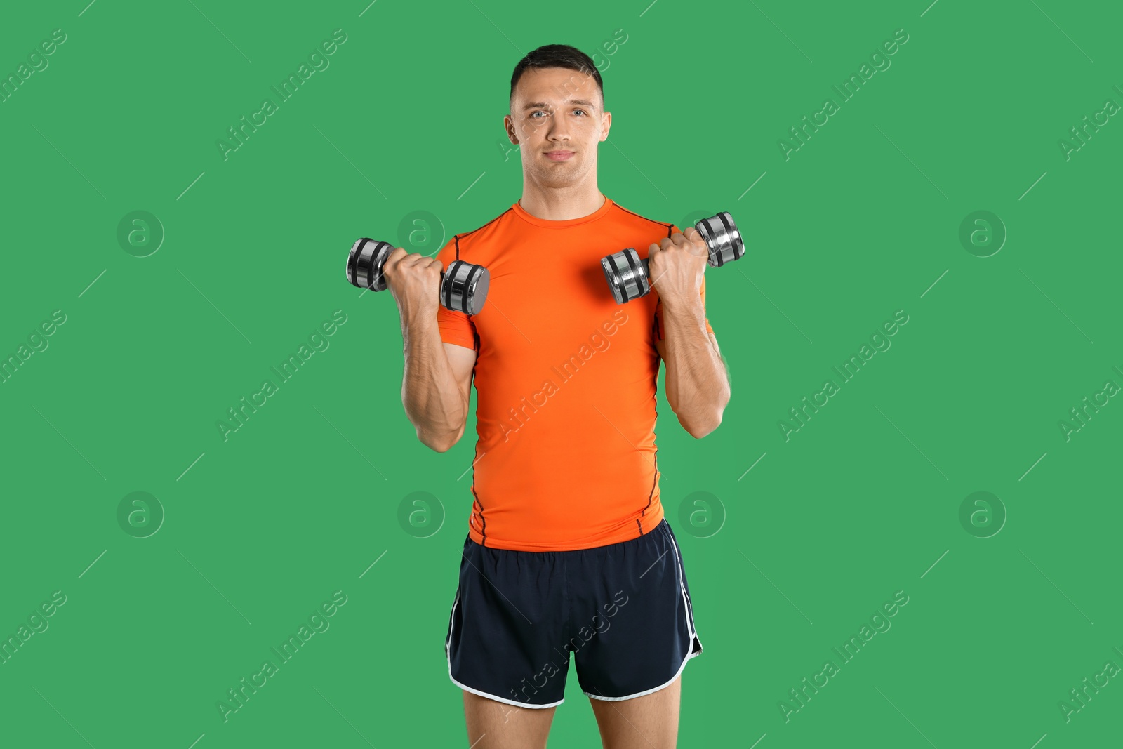 Photo of Man exercising with dumbbells on green background