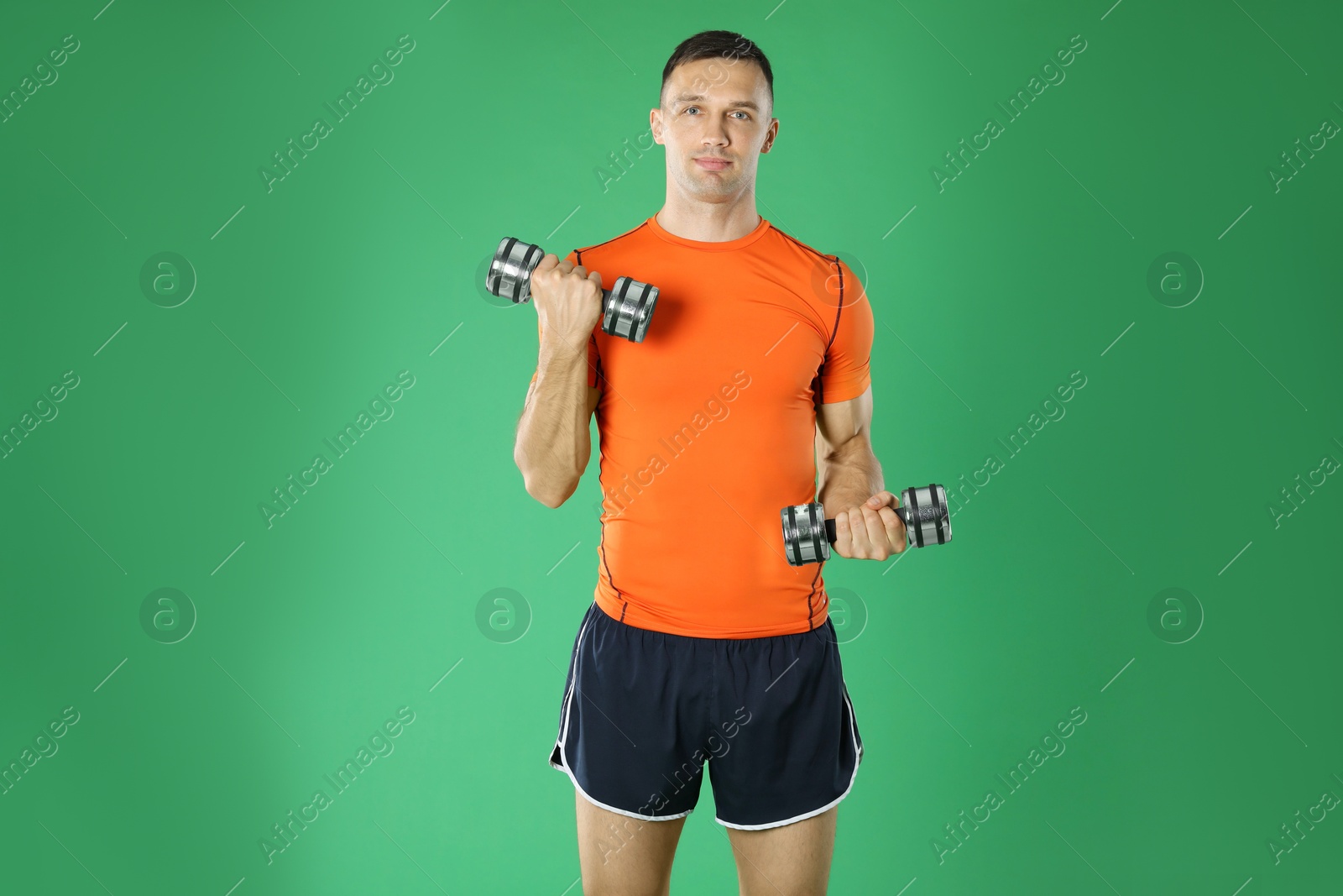 Photo of Man exercising with dumbbells on green background