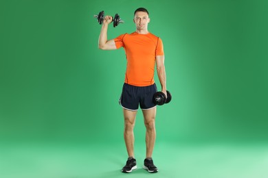 Photo of Man exercising with barbells on green background