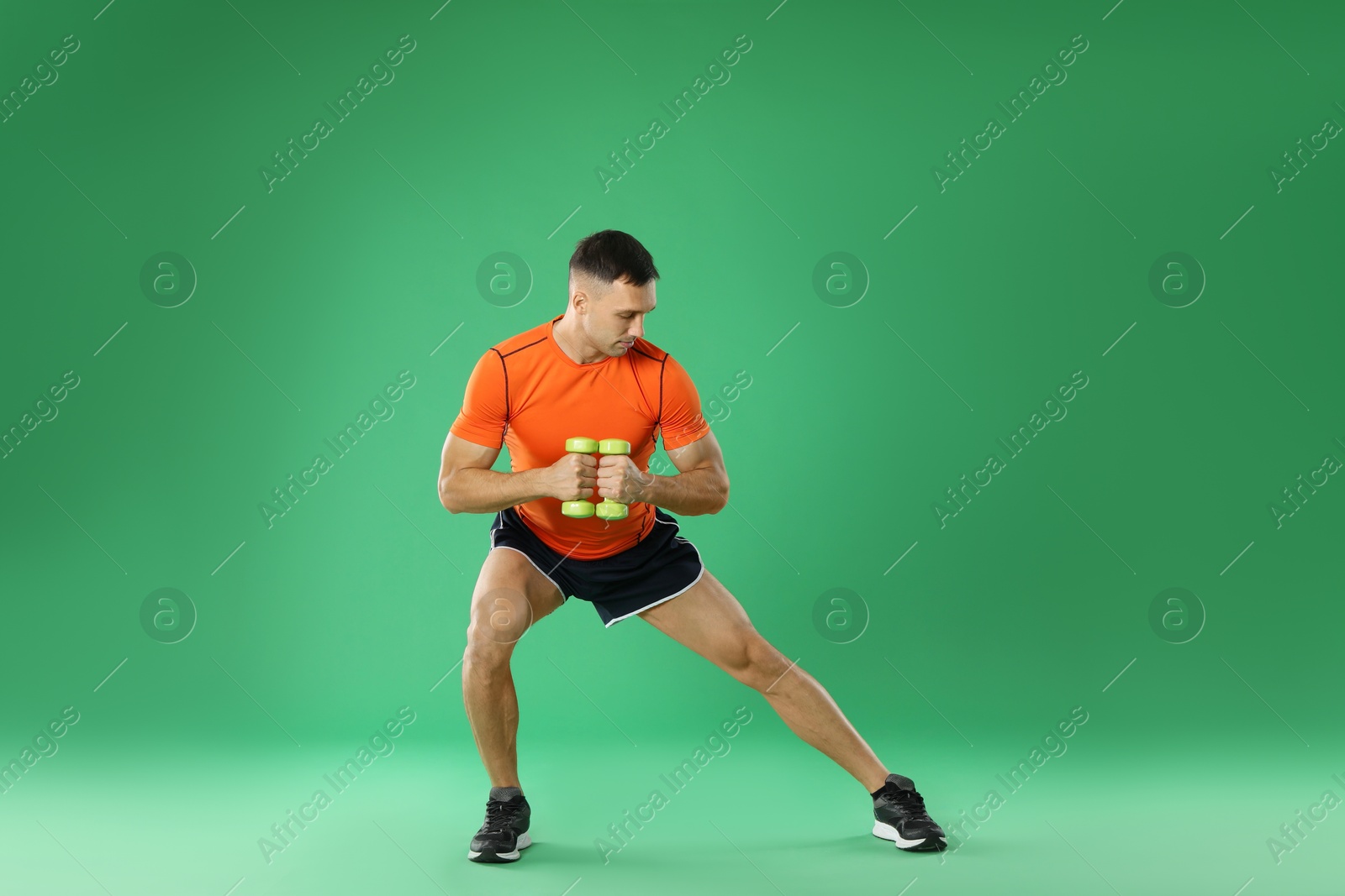 Photo of Man exercising with dumbbells on green background