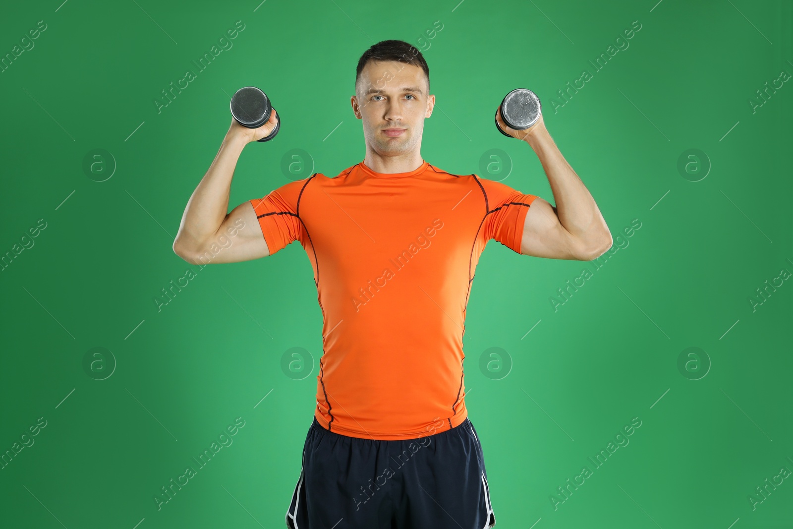 Photo of Man exercising with dumbbells on green background