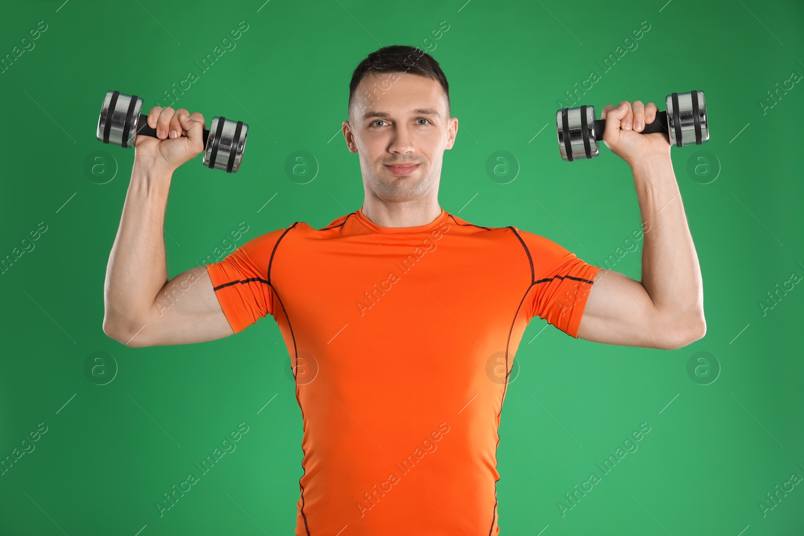 Photo of Man exercising with dumbbells on green background