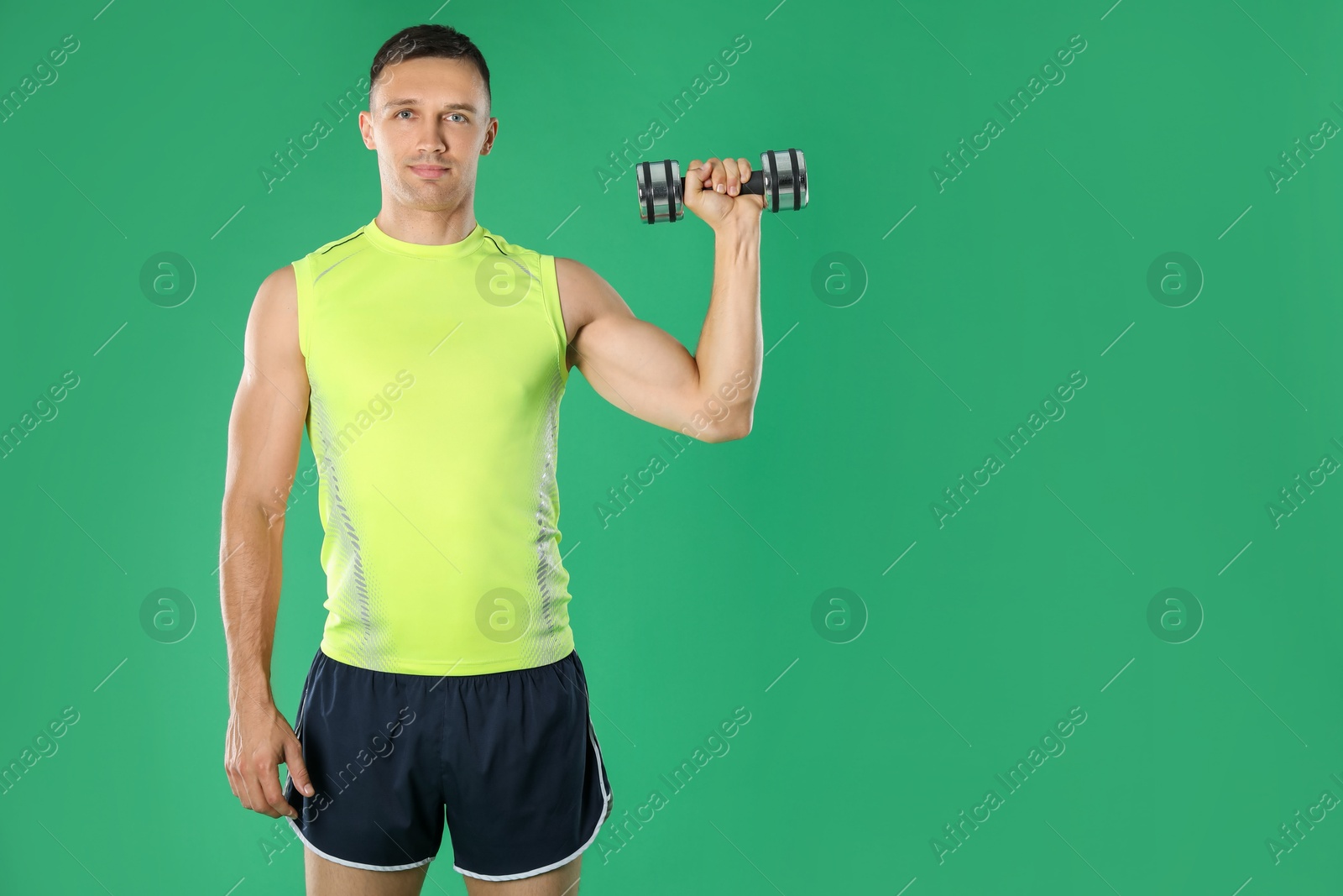 Photo of Man exercising with dumbbell on green background, space for text