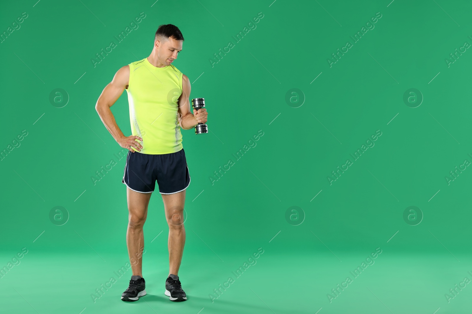 Photo of Man exercising with dumbbell on green background, space for text