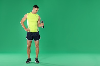 Photo of Man exercising with dumbbell on green background, space for text