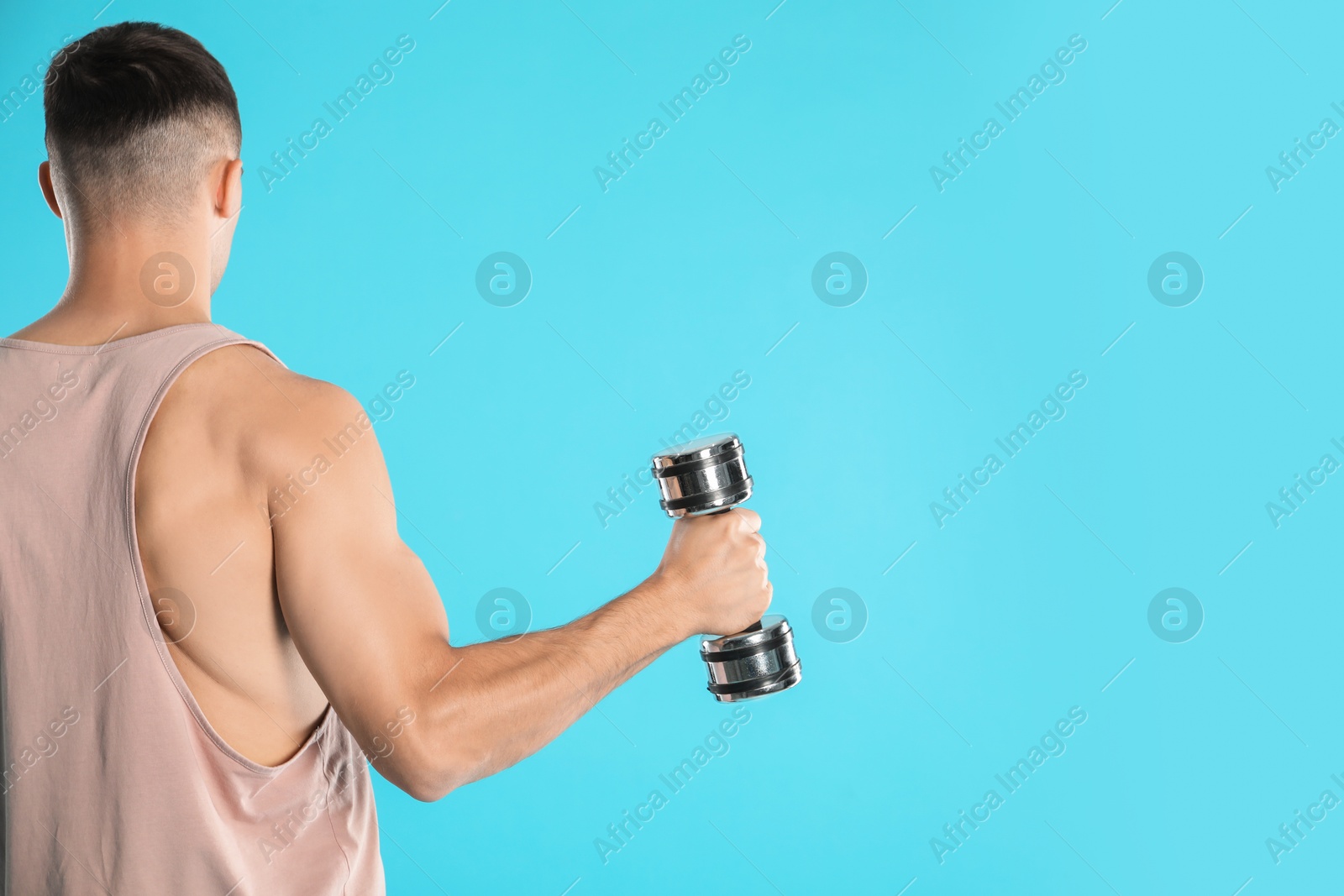 Photo of Man exercising with dumbbell on light blue background, back view. Space for text