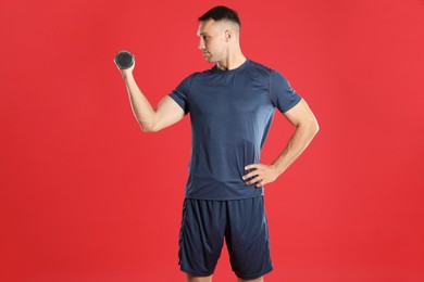 Photo of Man exercising with dumbbell on red background