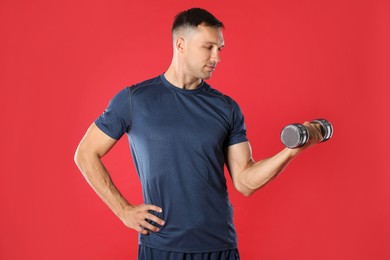 Photo of Man exercising with dumbbell on red background