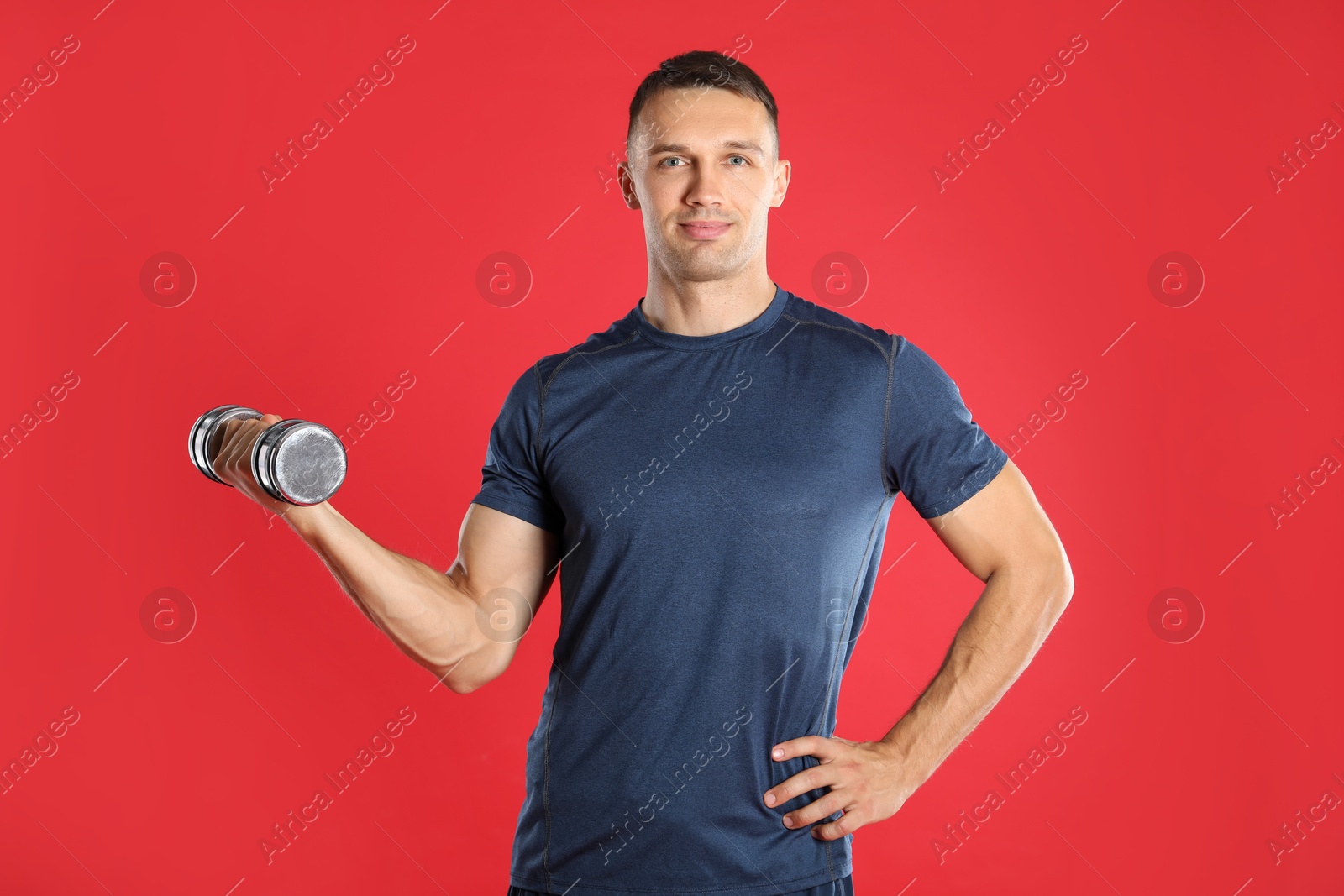 Photo of Man exercising with dumbbell on red background