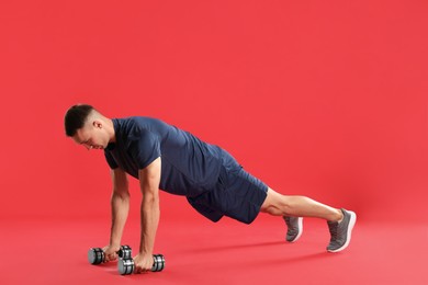 Photo of Man exercising with dumbbells on red background