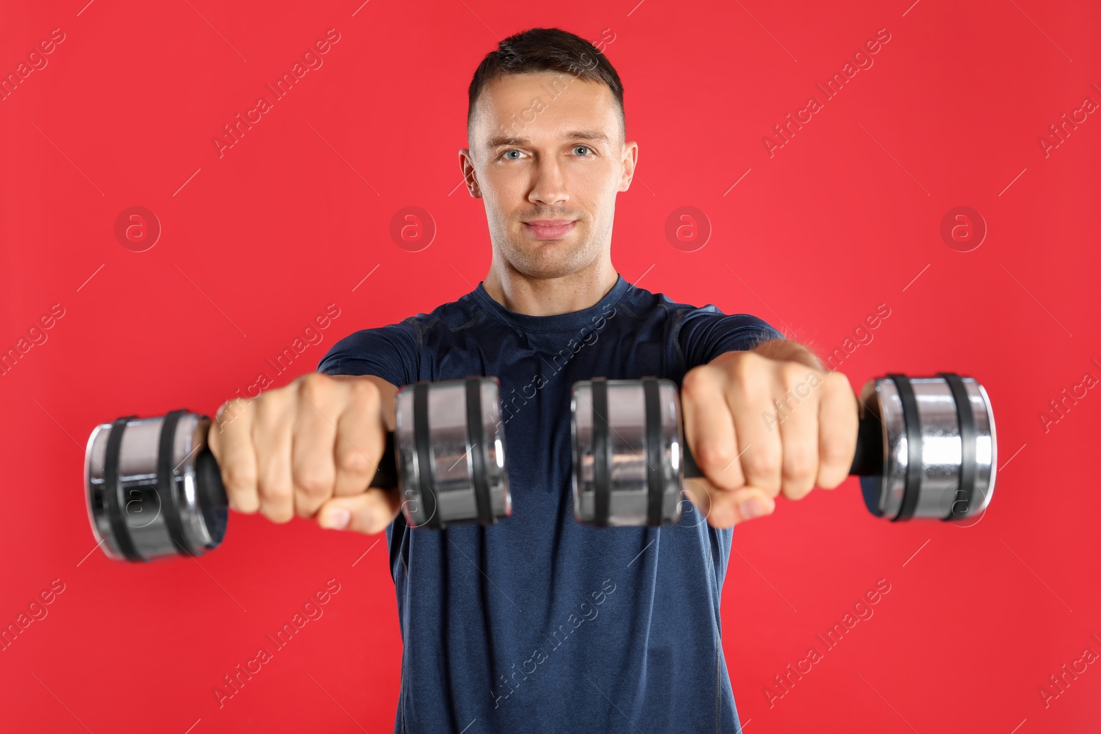 Photo of Man exercising with dumbbells on red background